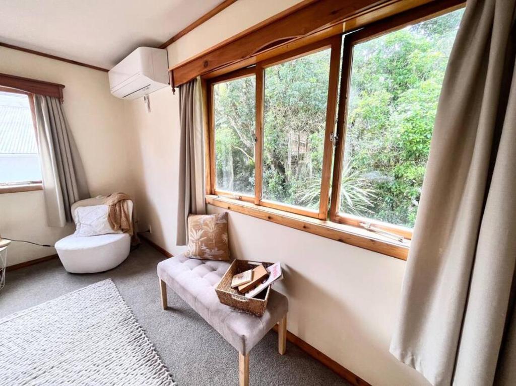 a living room with a chair and a window at Studio 6 at Tui Treehouse Stay Auckland in Auckland