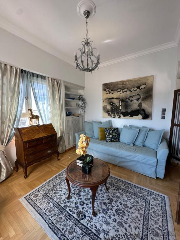 uma sala de estar com um sofá azul e uma mesa em 2 BD Apt in Syntagma with Acropolis view em Atenas