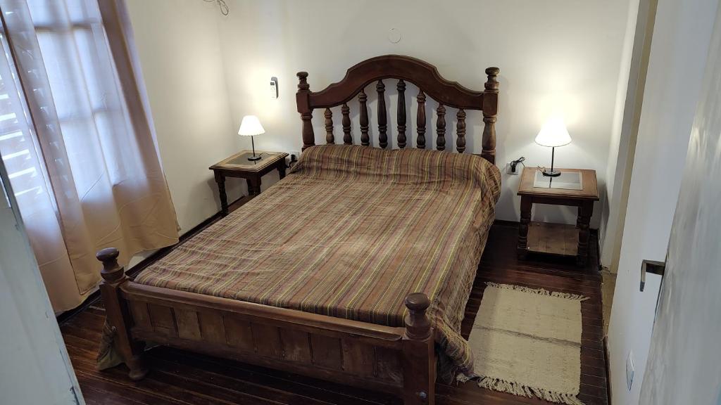 a large wooden bed in a room with two night stands at Departamento Avenida in Santo Tomé