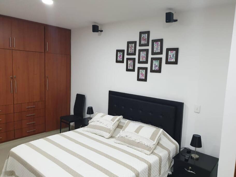 a bedroom with a large bed with pictures on the wall at Confort en zona ecológica, Loft en Pilarica 2 in Medellín