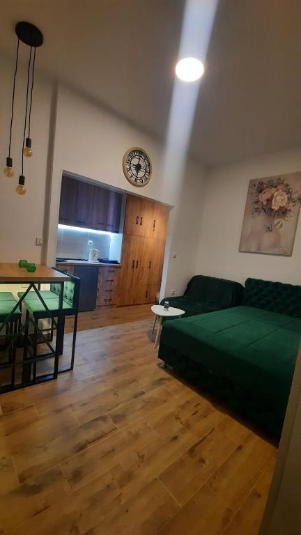 una sala de estar con una cama verde y una mesa. en Apartman GreenPine, en Soko Banja