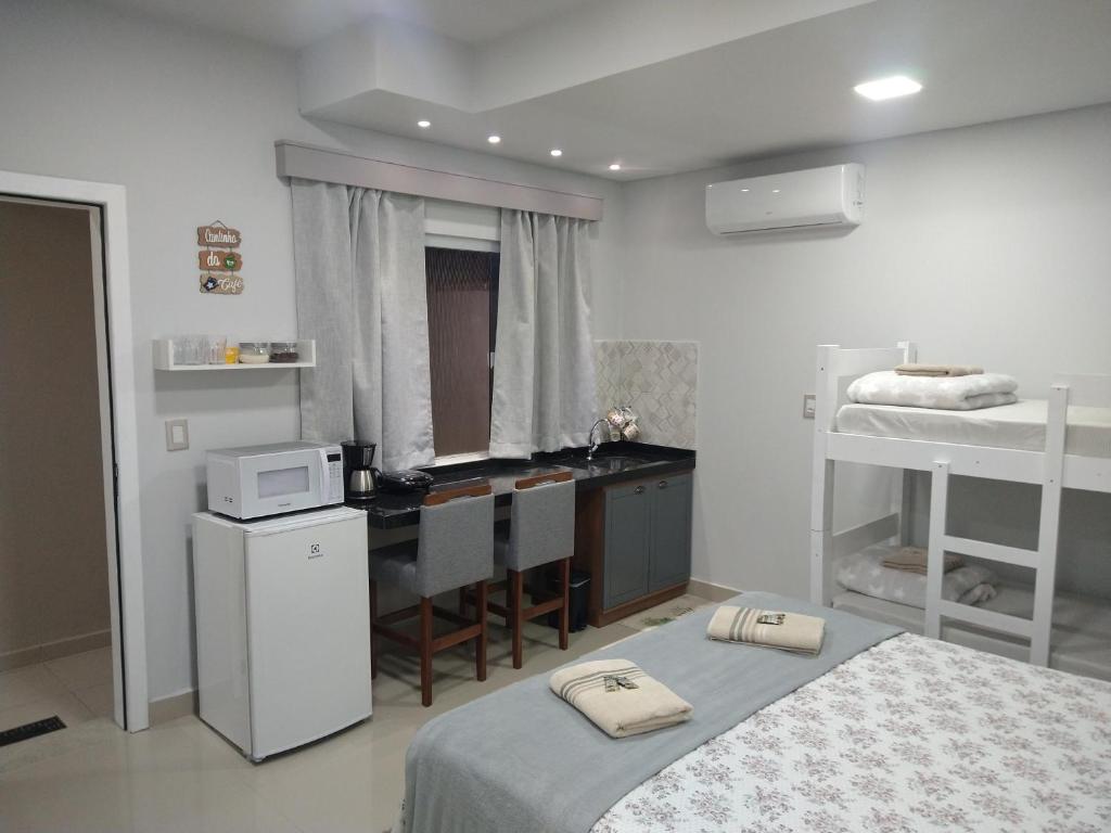 a room with two beds and a kitchen and a desk at Cantinho da Vila Hospedagem in Penha