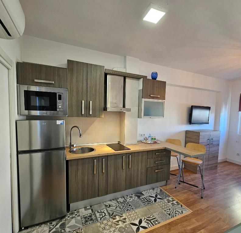 Il comprend une cuisine équipée d'un réfrigérateur en acier inoxydable et d'une table. dans l'établissement Precioso apartamento con estilo., à Almería
