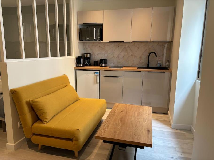 uma sala de estar com um sofá amarelo e uma mesa em Cocon 2 calme en cœur historique em Périgueux