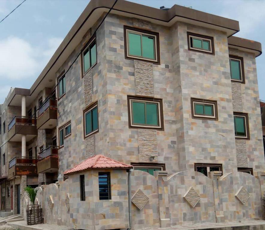 a tall stone building with green windows on it at Luxury House in Porto-Novo