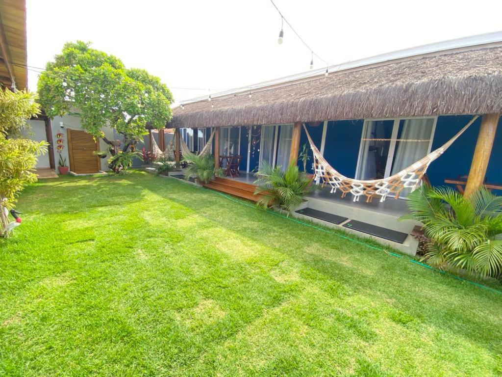 a yard in front of a house with a hammock at Noah Hostel & Chale in São Miguel do Gostoso