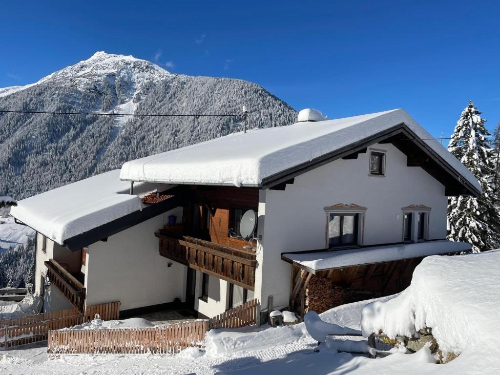 een huis bedekt met sneeuw met een berg op de achtergrond bij Ferienhaus Wolf in Tobadill