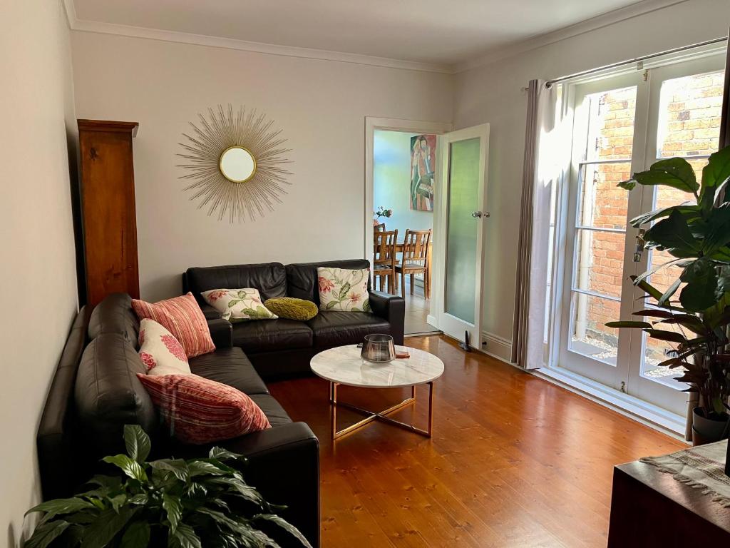 een woonkamer met een bank en een tafel bij Lovely Victorian Terrace - Entire home in Melbourne