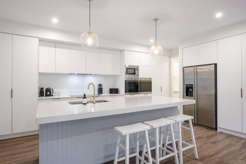 a kitchen with white cabinets and a counter with stools at Schnapper Lane in Warrnambool