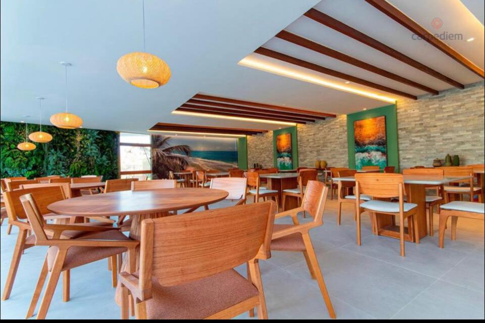 uma sala de jantar com mesas e cadeiras de madeira em Mana Beach Experience -02Garagens - Aloha 001 em Ipojuca