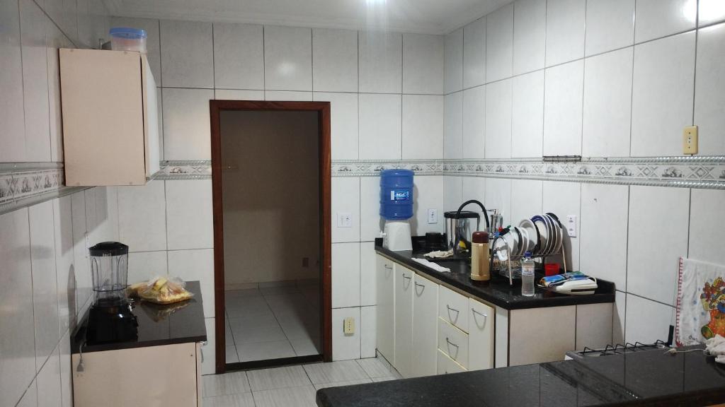 a kitchen with a door open to a kitchen with white tiles at HOSTEL VENDA NOVA in Belo Horizonte