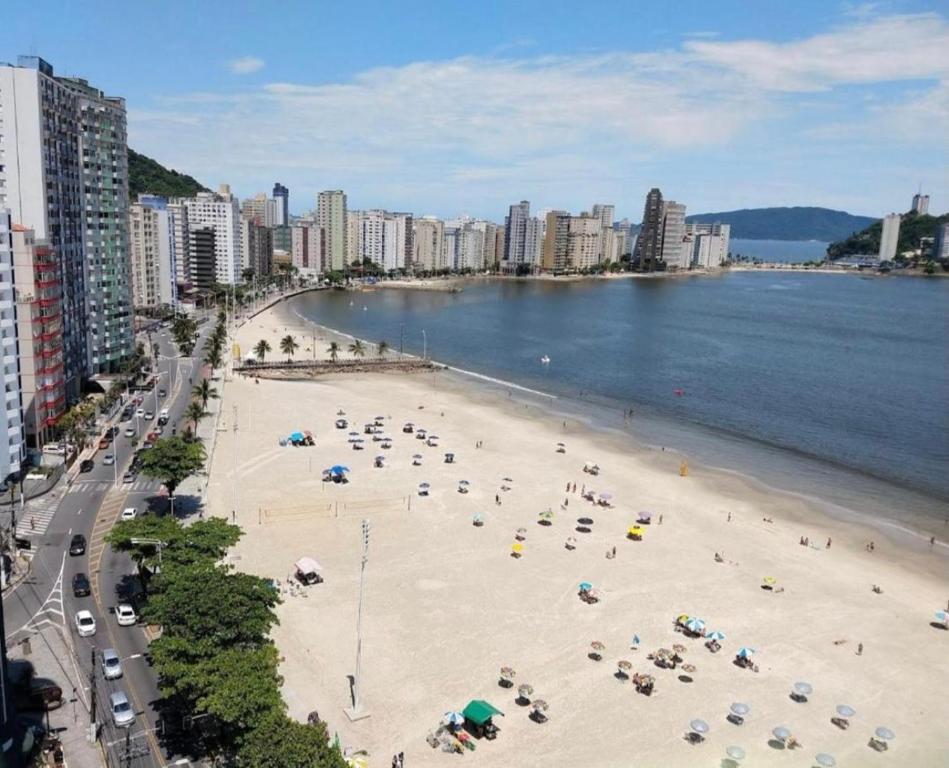 a beach with many umbrellas and people on it at Apartamento Flat Palladium in São Vicente