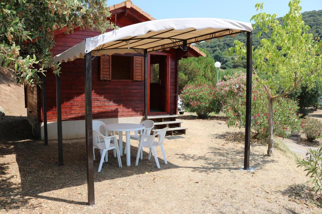 a table and chairs under a canopy in front of a house at Camping Les Couchants in Casaglione