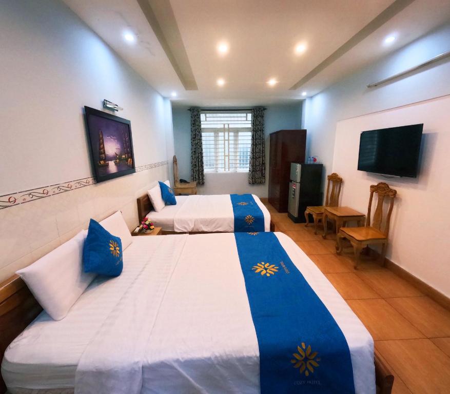 a hotel room with two beds and a flat screen tv at COZY Hotel HCM in Ho Chi Minh City