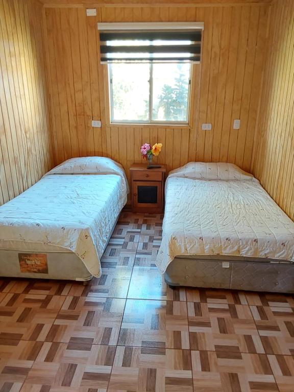 2 Betten in einem kleinen Zimmer mit Fenster in der Unterkunft Suit Victoria (2 camas singles) in Hanga Roa