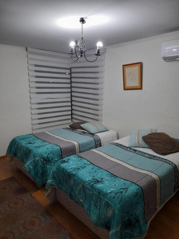 2 camas en un dormitorio con lámpara de araña en Parcela Zurich, casa 1, en Angol