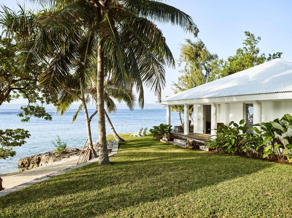 a house with a palm tree next to the ocean at Tamarind Beach Estate in Port Vila