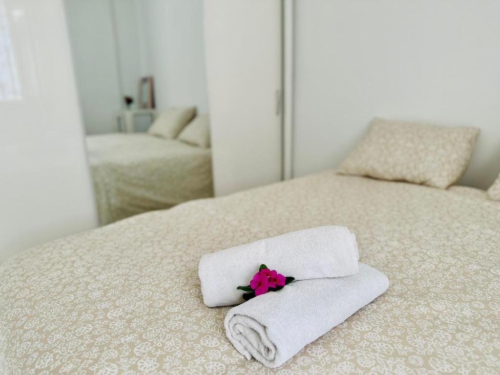 a bed with towels and a pink flower on it at Dar almasyaf, maison bord de mer in Gabès