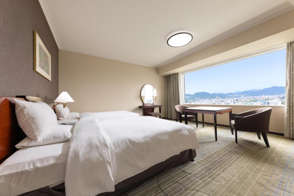 a hotel room with a bed and a desk and a window at Rihga Royal Hotel Hiroshima in Hiroshima