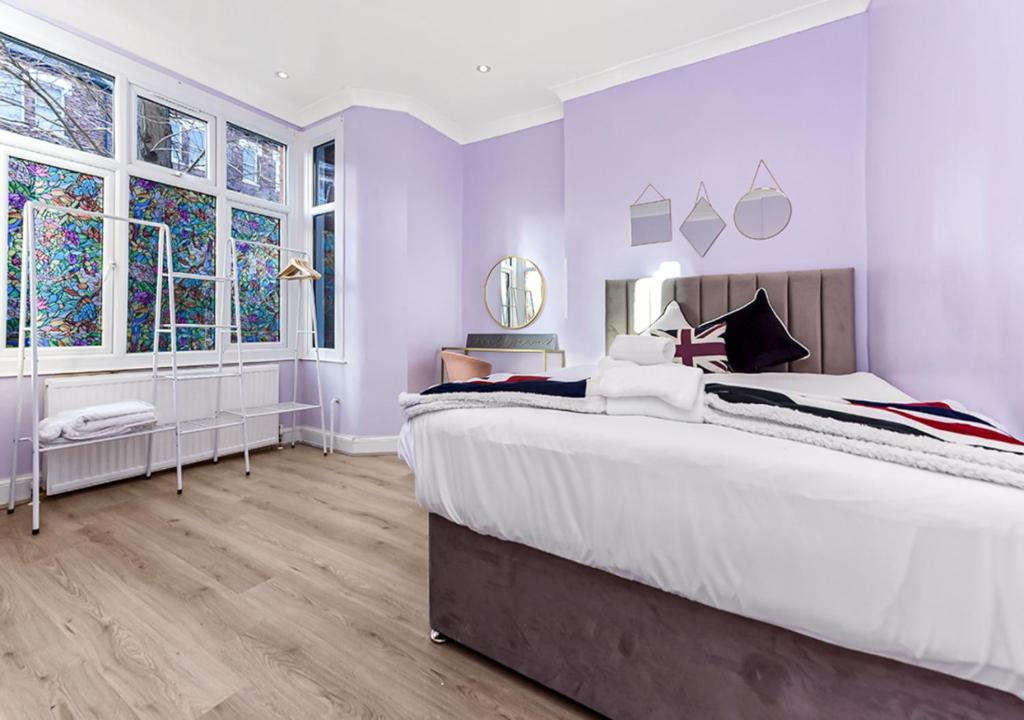a purple bedroom with a large bed and windows at Amazing 2 Bedroom flat in London in London