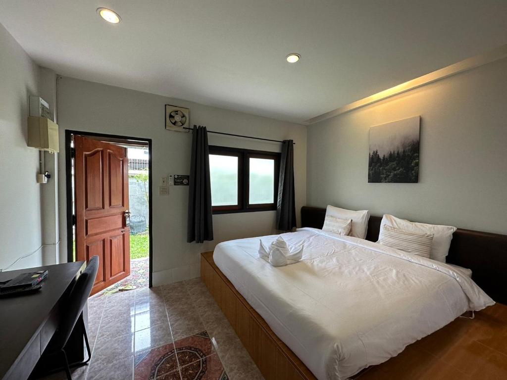 a bedroom with a large white bed and a window at Baan Ma Feung GuestHouse in Kanchanaburi