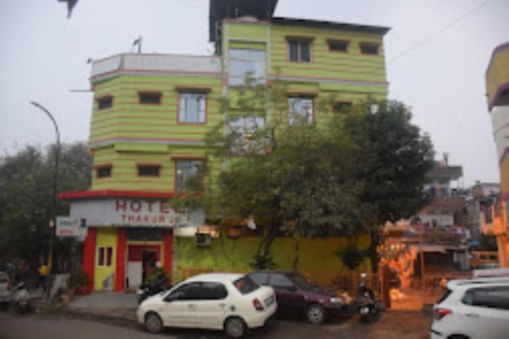 ein großes gelbes Gebäude mit davor geparkt in der Unterkunft HOTEL THAKUR JI,Bhopal in Bhopal