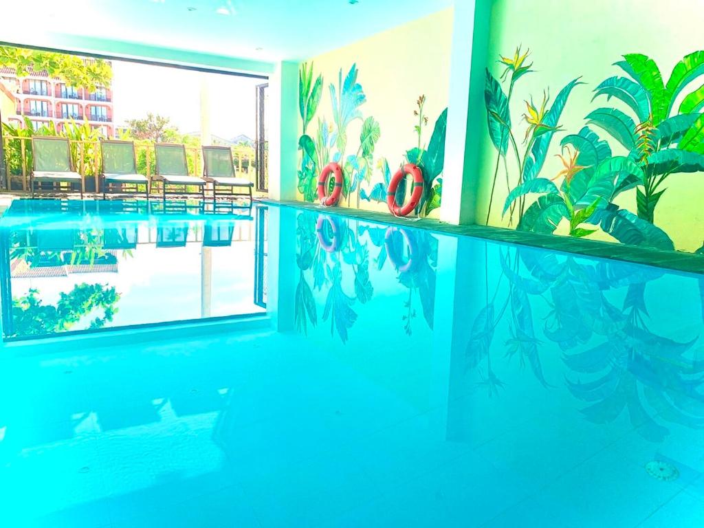 a swimming pool in a room with a painting on the wall at Aman Boutique Hotel in Hoi An