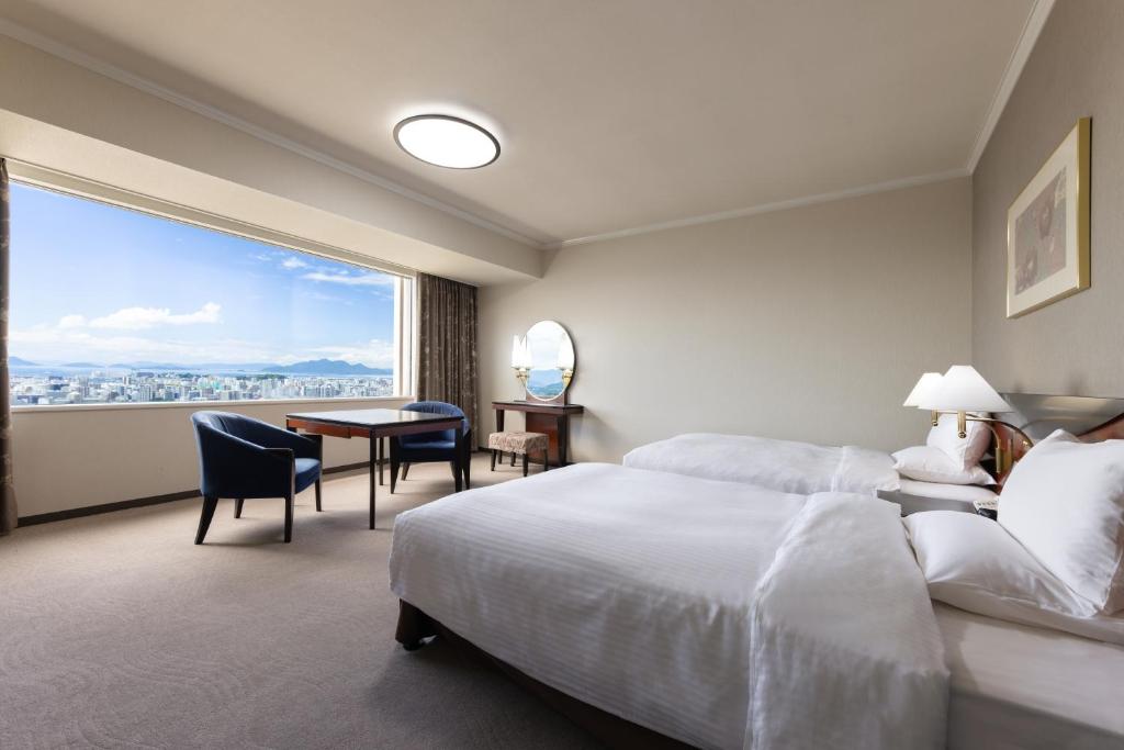a hotel room with two beds and a desk and a window at Rihga Royal Hotel Hiroshima in Hiroshima