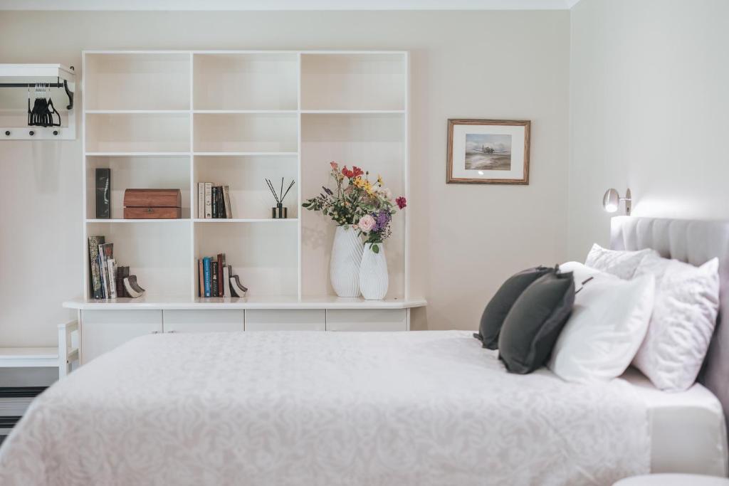 Un dormitorio blanco con una cama con flores. en Birches Mudgee, en Mudgee