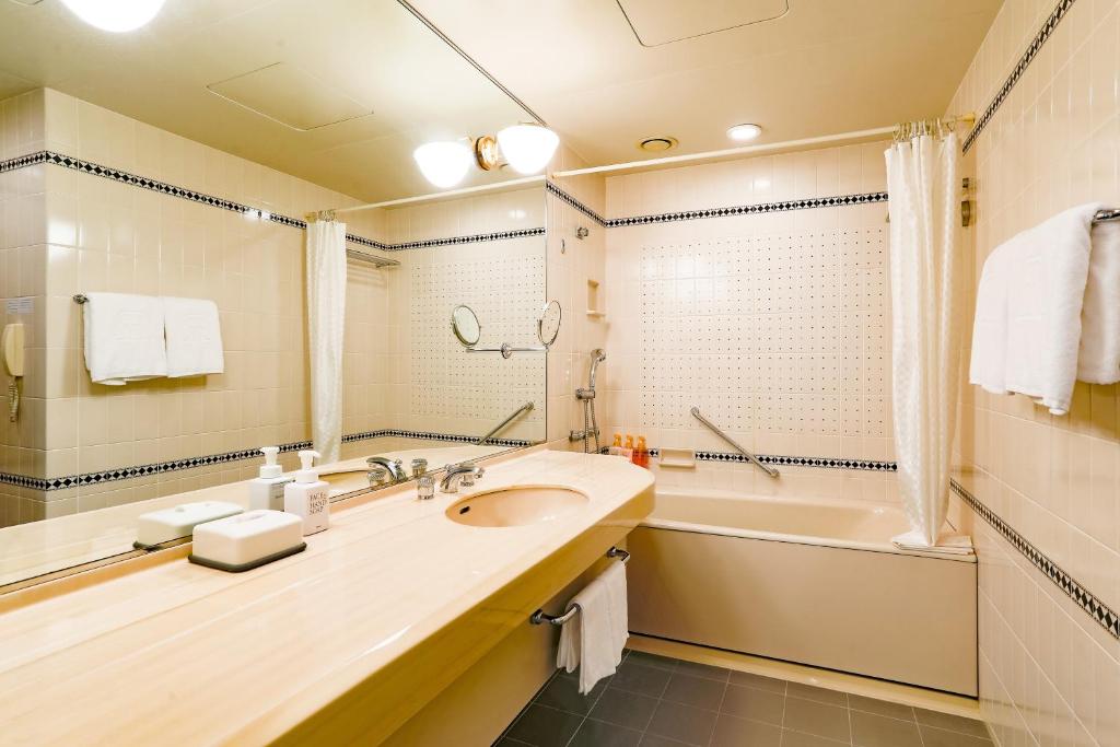 a bathroom with a sink and a bath tub and a tubermottermott at Rihga Royal Hotel Hiroshima in Hiroshima