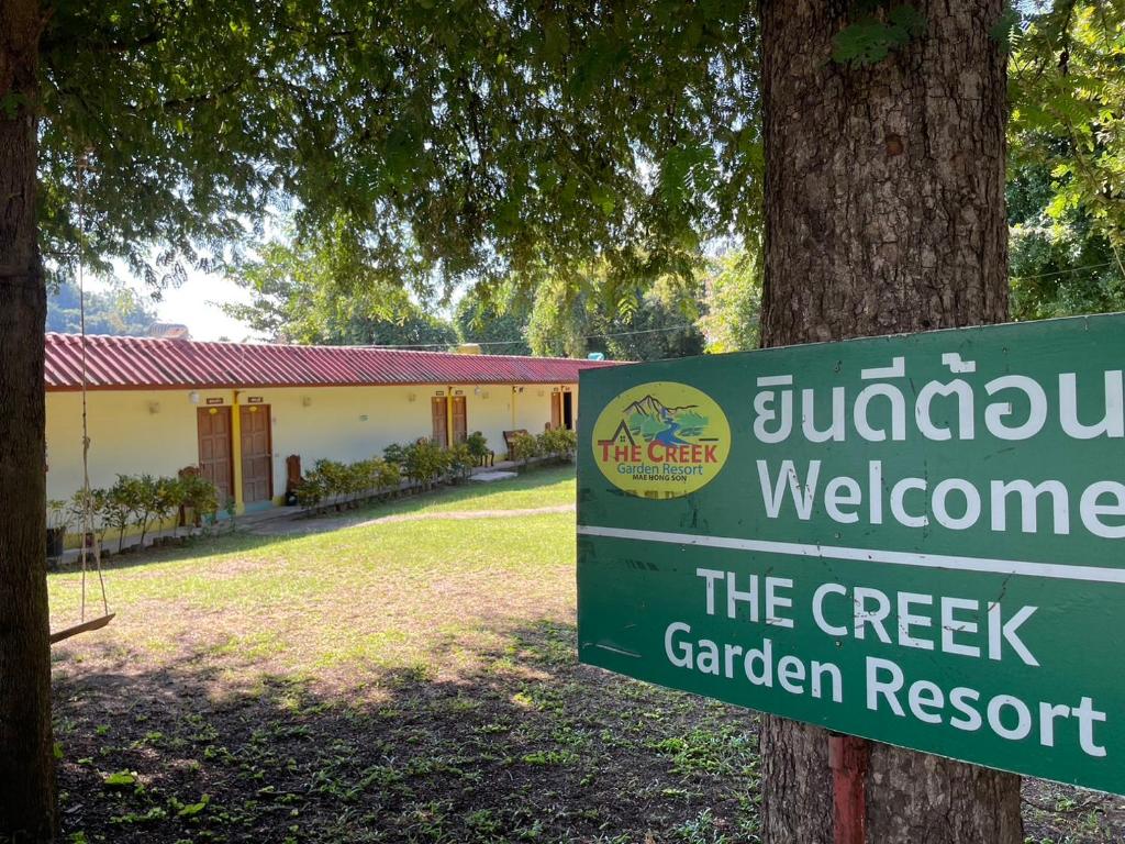 a sign for the creek garden resort next to a tree at The Creek Garden Resort Huainamrin ห้วยนำ้ริน in Mae Hong Son