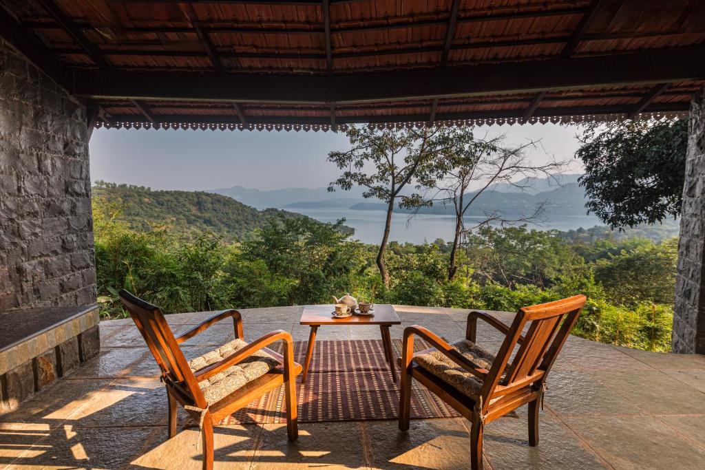 una mesa y 2 sillas en un patio con vistas en SaffronStays Sunkissed - 2 Bedroom Pet-friendly Infinity Pool Villa in Mulshi, en Mulshi