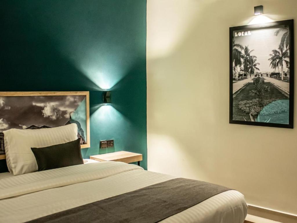 1 dormitorio con cama y pared verde en LOKAL Rooms x Shahrah-e-Faisal (Nursery) en Karachi