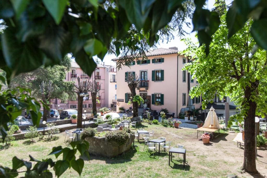 un parque con sillas, mesas y edificios en Hotel Fabbrini, en Abbadia San Salvatore