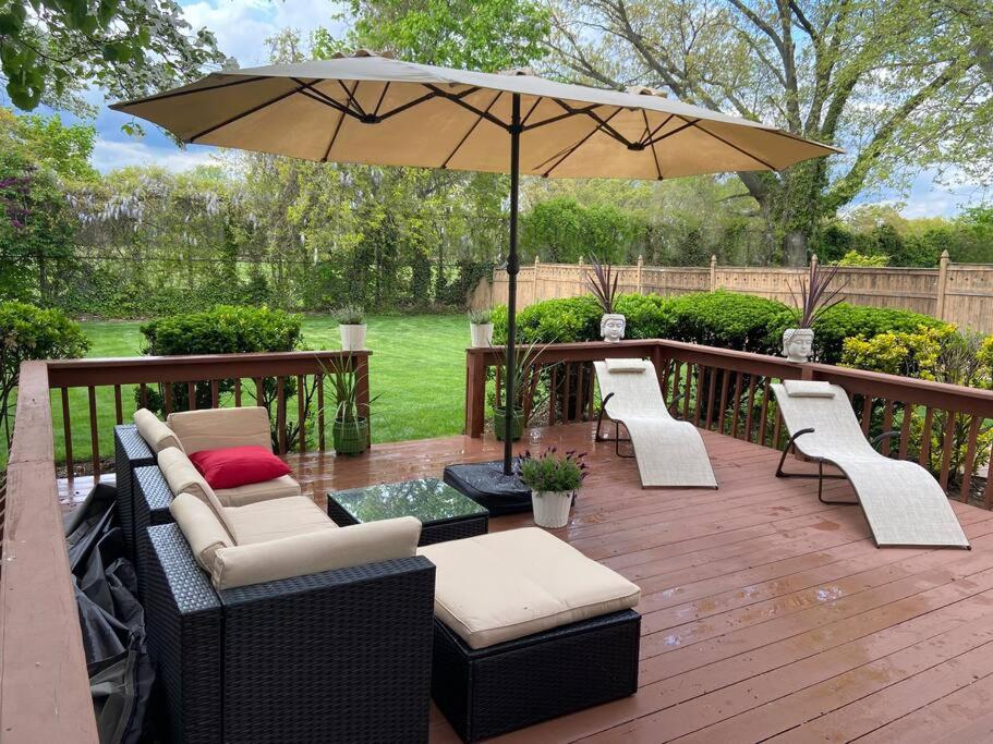 a patio with chairs and an umbrella on a deck at BBQ, Beats, Hot Tub Retreat in Baldwin