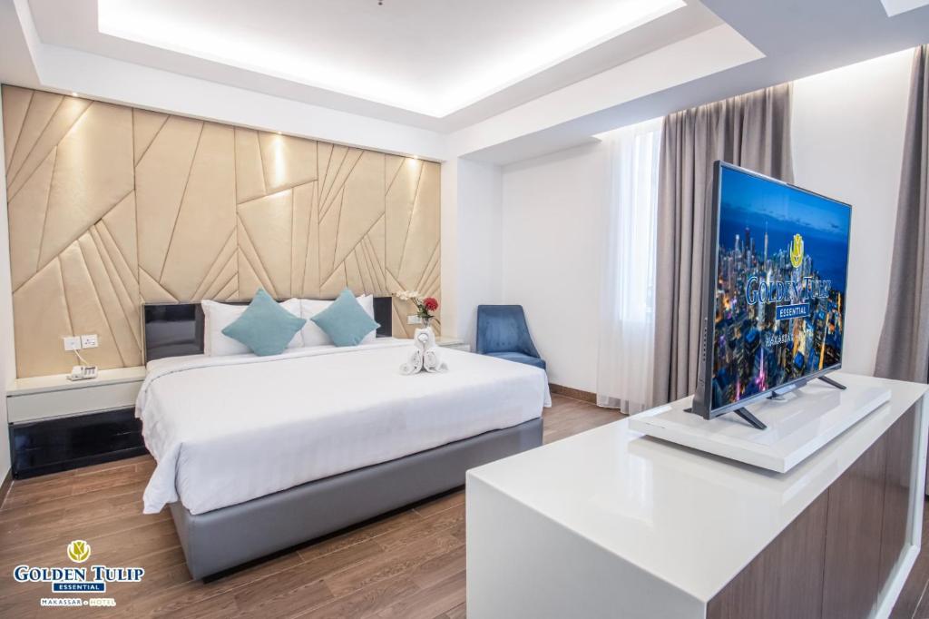 a hotel room with a bed and a flat screen tv at Golden Tulip Essential Makassar in Makassar