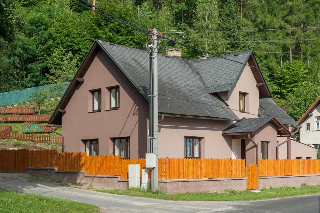 ein rosa Haus mit schwarzem Dach und einem orangenen Zaun in der Unterkunft U Housenky in Klokočí