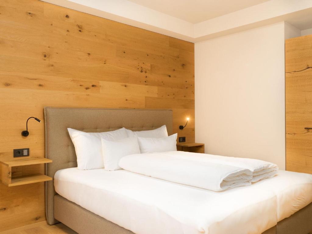 a bedroom with a white bed with a wooden wall at My Heimat 1495 Arlberg in Schröcken