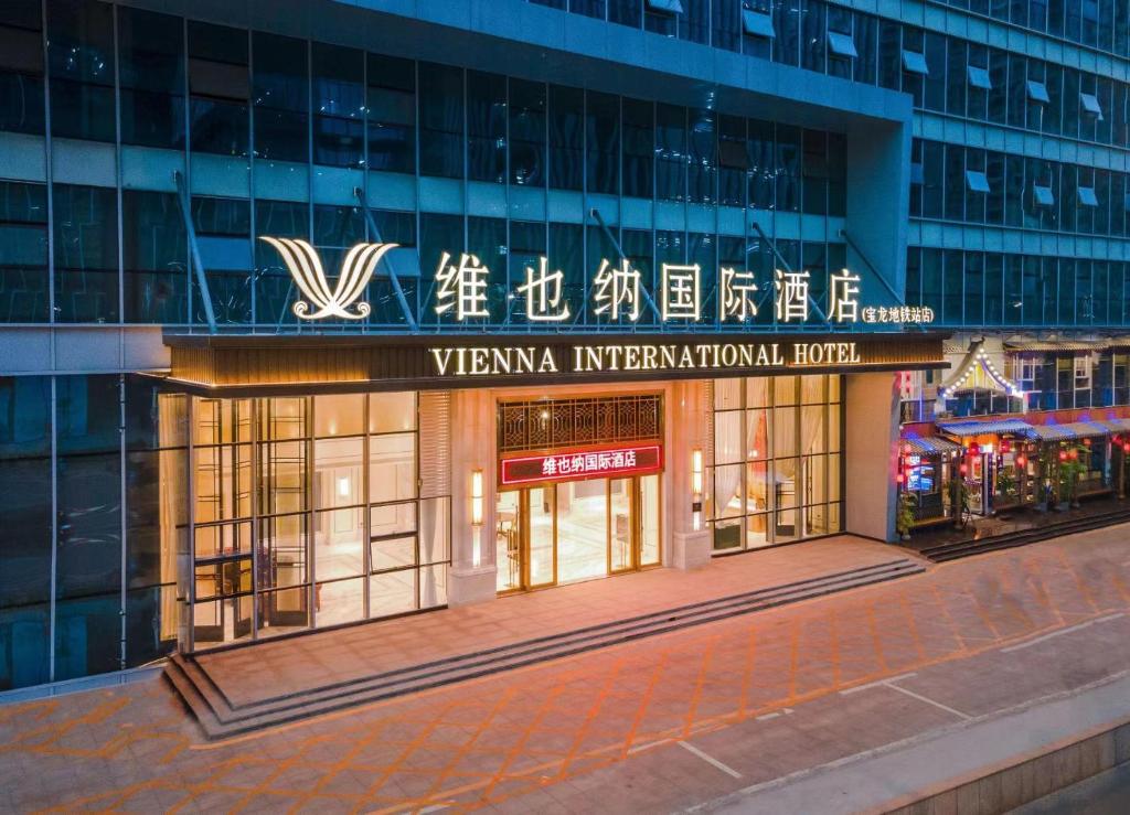 Vienna International Hotel Shenzhen Baolong subway Station branch في Longgang: مبنى عليه لوحة مكتوب عليها فندق ڤينا الدولي