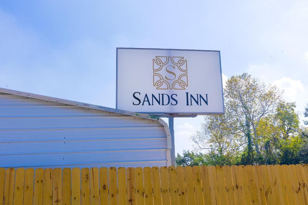 um sinal para a estalagem de areias ao lado de uma cerca em Sands Inn by OYO Winnie em Winnie