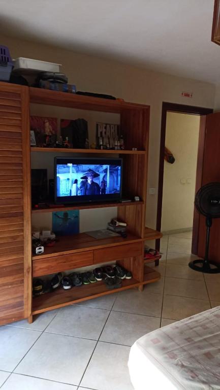 uma televisão numa prateleira de madeira num quarto em Apartamento condomínio Vila la Torre em Porto Seguro