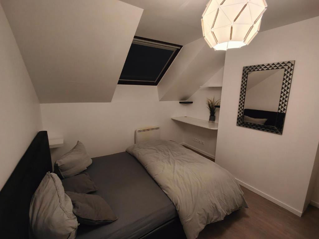 ein kleines Schlafzimmer mit einem Bett und einem Spiegel in der Unterkunft Les Lofts De Provins: Apt 8 in Provins