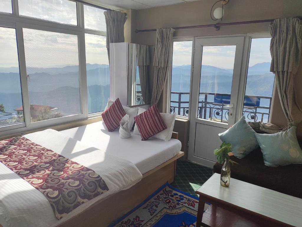 a hotel room with a bed and a large window at Hotel High Ground Inn Sarangkot in Pokhara