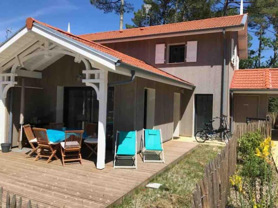 een huis met een houten terras met blauwe stoelen bij La Cigale du Pyla, au cœur de l'écoquartier avec piscine commune in La Teste-de-Buch