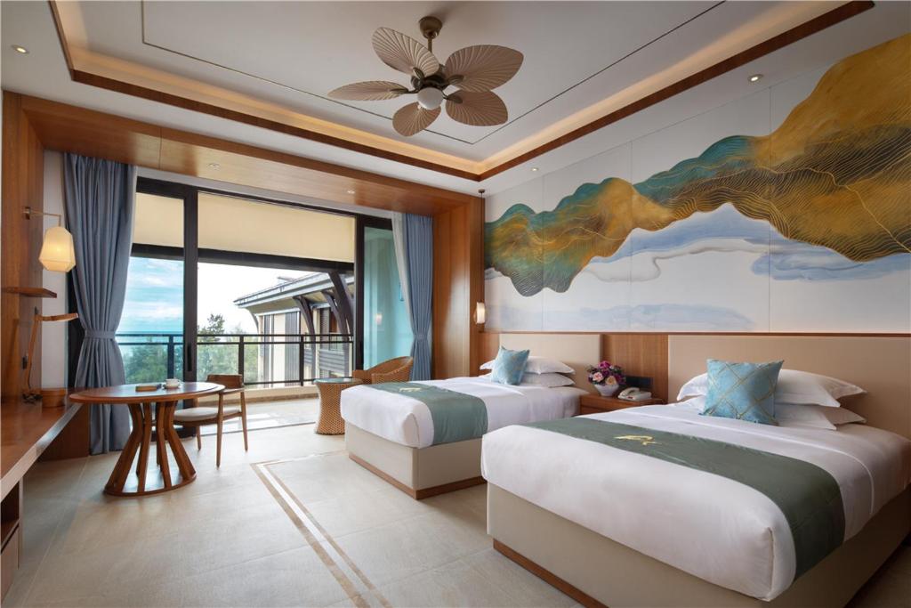 a bedroom with two beds and a painting on the wall at Arcadia Resort Hainan in Lingshui