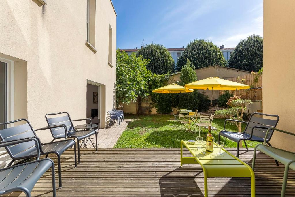 eine Terrasse mit Tischen, Stühlen und gelben Sonnenschirmen in der Unterkunft MAISON EOLE in Villeurbanne