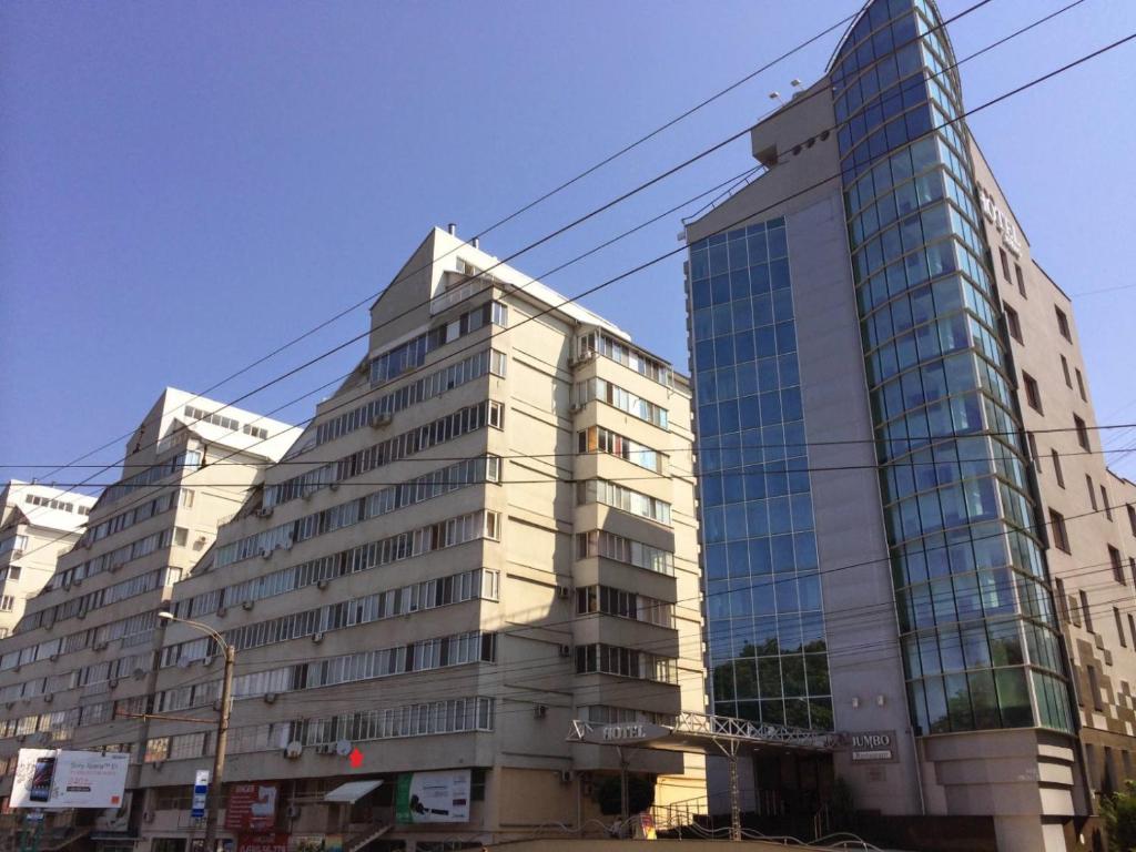 a tall building with glass windows in a city at Decebal Residence in Chişinău