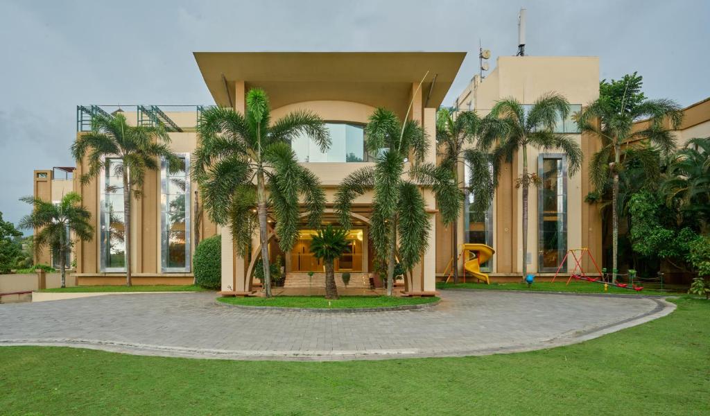 a building with palm trees in front of a playground at Flora Airport Hotel and Convention Centre Kochi in Nedumbassery