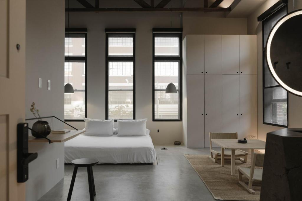 a bedroom with a bed and a table and some windows at kodō hotel in Los Angeles