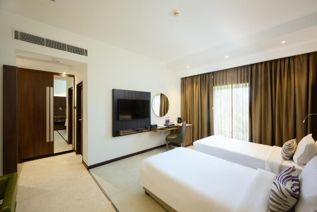 a hotel room with a bed and a television at Flora Airport Hotel and Convention Centre Kochi in Nedumbassery